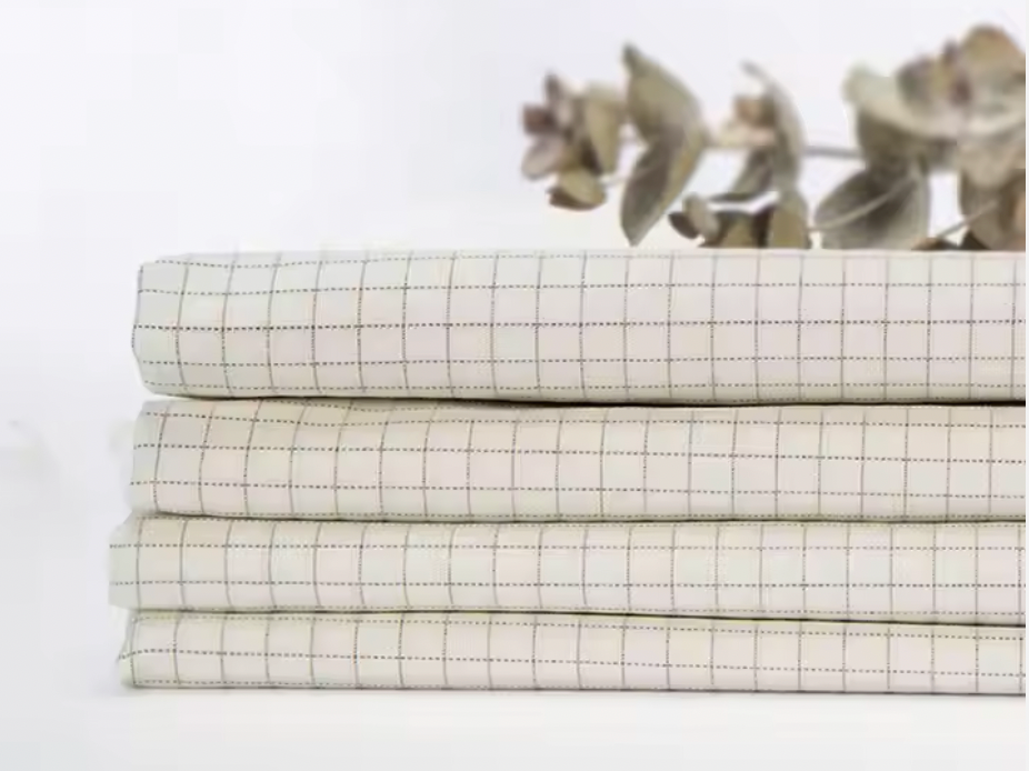 Folded grounding sheets with grid design, made from natural fabrics for earthing and better sleep, displayed with eucalyptus leaves.