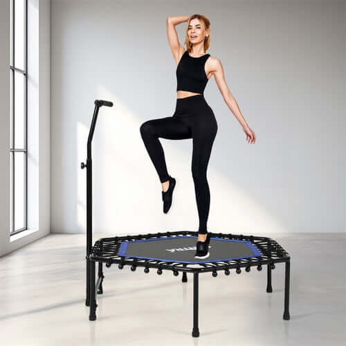 Woman exercising on a mini trampoline with a handlebar, performing a low-impact cardio workout in a bright and modern fitness space.