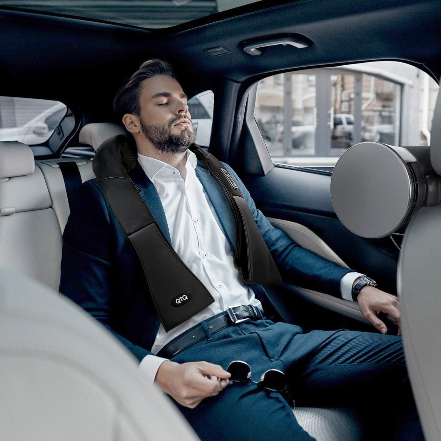 Man using neck massager with heat while relaxing in the backseat of a car, ideal for travel stress relief and muscle recovery