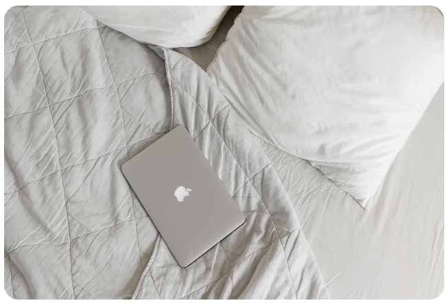 Bed with grounding sheet and pillows, featuring a quilted design with a laptop on top, showing earthing bedding for better sleep