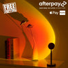 Sunset lamp casting a warm orange and yellow gradient on the wall, creating a cozy atmosphere in a minimalist room setting with books and decor.