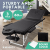 Sturdy and portable massage table with black cushioning, adjustable headrest, and foldable metal legs, suitable for professional or home use.